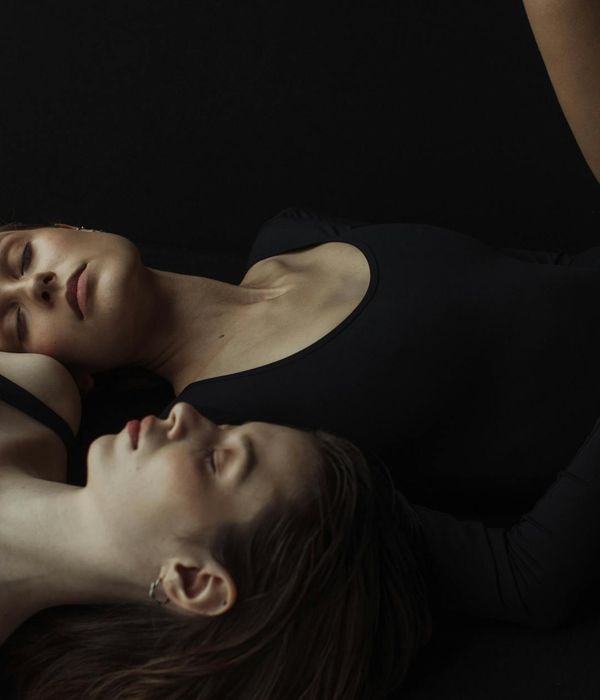 Woman in a serene yoga pose against a calm, dark background.